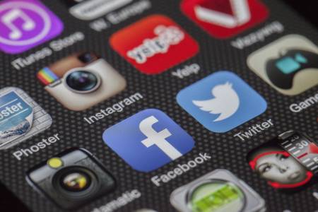 Een telefoonscherm met verschillende apps met onder anderen Instagram, Facebook, Twitter en Yelp.