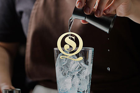 logo van Sloq op een foto met een barman die een glas inschenkt met een afgemeten shot